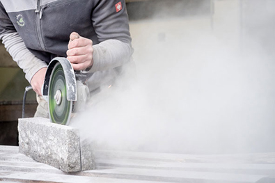 Zuschnitt einer Palisade aus Naturstein mit einer Flex.