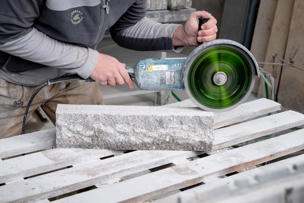 Ein Mitarbeiter der Firma Löseke´s Steingarten beim durchschneiden einer Palisade auf Maß.